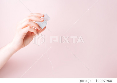 Dental floss in a female hand against a pink background Dental floss in a female hand against a pink background 100979881