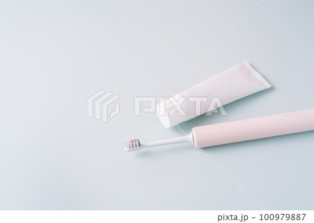 Pink electric toothbrush with toothpaste on a blue background Pink electric toothbrush with toothpaste on a blue background 100979887