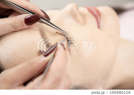 まつ毛エクステの施術を受ける女性のアップ 100980126