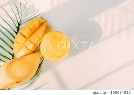 top view and flat lay summer fruit from mango slice and juice with shadow of tropical leaf and white background 100984039
