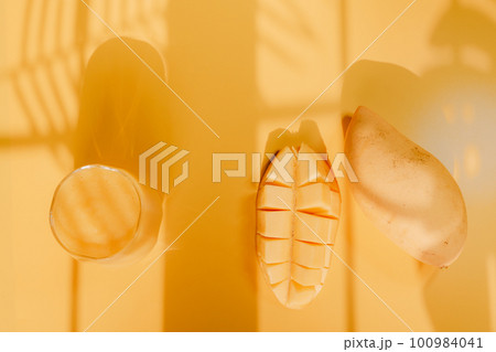 top view and flat lay summer fruit from mango slice and juice with shadow of tropical leaf and yellow background 100984041