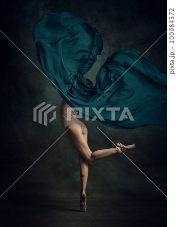 Portrait of young ballerina dancing with fabric over dark background. Back view Portrait of young ballerina dancing with fabric over dark background. Back view 100984372