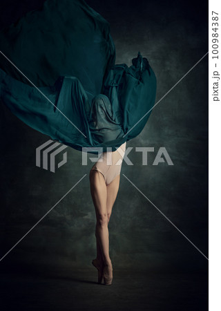 Young girl dancing with elegance movements and fabric cover the face over dark green background 100984387