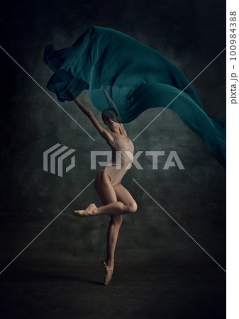 Tender beautiful ballerina wearing beige bodysuit in action with navy silk cloth over dark green background Tender beautiful ballerina wearing beige bodysuit in action with navy silk cloth over dark green background 100984388