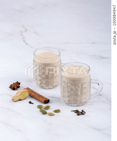 Glass cups with masala tea and cinnamon, anise with cloves and ginger root with cardamom. Glass cups with masala tea and cinnamon, anise with cloves and ginger root with cardamom. 100984947
