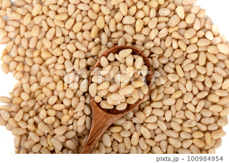 Top view of peeled pine nuts and wooden spoon with pine nuts. 100984954