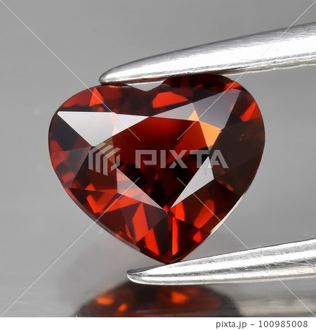 Natural gemstone red spessartine garnet on a gray background Natural gemstone red spessartine garnet on a gray background 100985008