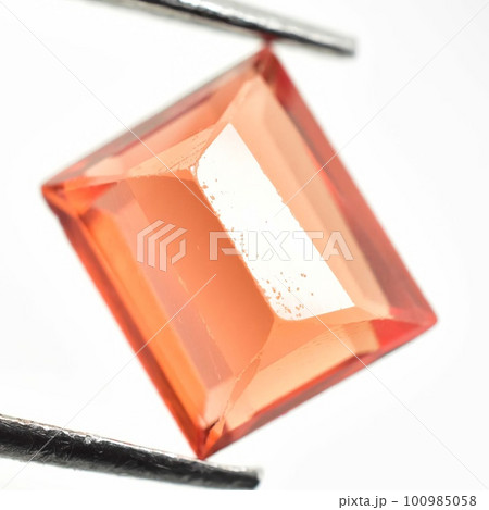 Natural gemstone orange Padparadscha sapphire on gray background 100985058