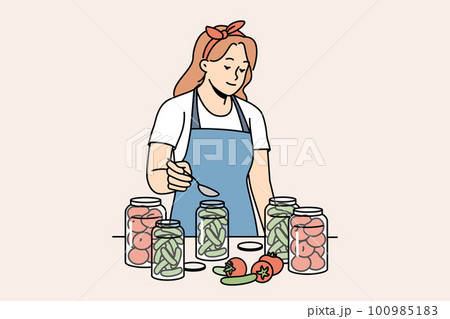 Woman in apron canning vegetables in bottles Woman in apron canning vegetables in bottles 100985183