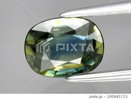 Natural gemstone green sapphire on gray background Natural gemstone green sapphire on gray background 100985723