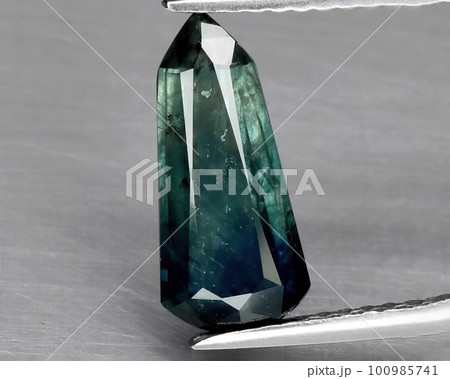 Natural gemstone green sapphire on gray background 100985741