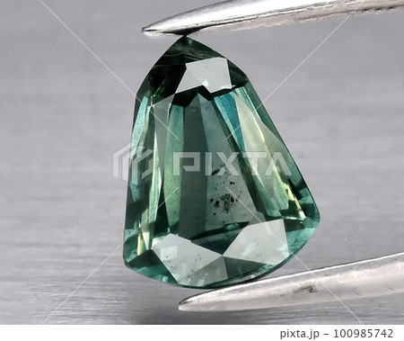 Natural gemstone green sapphire on gray background 100985742