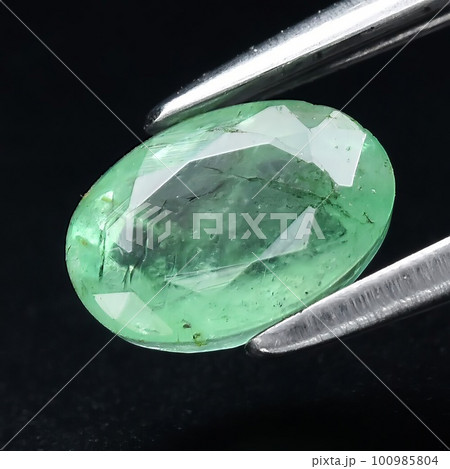 Natural gemstone green emerald on gray background 100985804