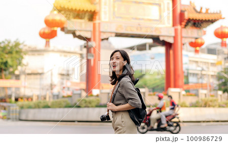Young Asian woman backpack traveler enjoying China town street food market in Bangkok, Thailand. Traveler checking out side streets. 100986729