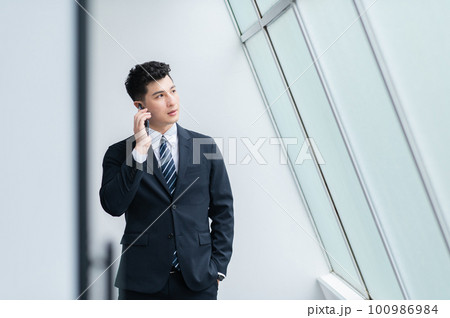 スマホで電話する若いビジネスマン 100986984