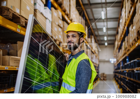 Portrait of warehouse worker carring solar panel. 100988082