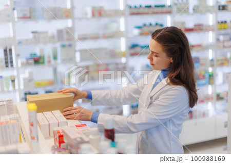 Young pharmacist checking medicine stock in pharmacy. 100988169