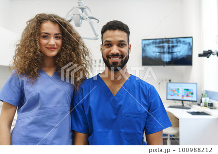 Portrait of young dentist and his nurse at private dental clinic. 100988212