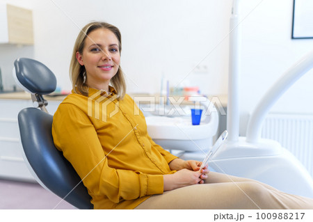 Portrait of young woman in dentist chair. 100988217