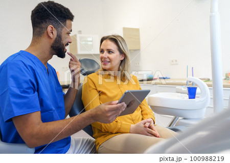 Young woman having consultation with multiracial dentist. 100988219