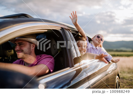 Happy family enjoying drive in their new electric car. 100988249
