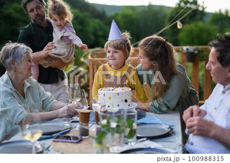 Multi generation family celebrating birthday and have garden party outside in the backyard on patio. Multi generation family celebrating birthday and have garden party outside in the backyard on patio. 100988315