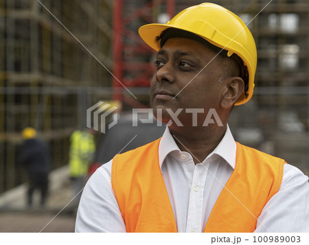 Profile portrait of an absorbed civil engineer or factory worker wearing a safety helmet and looking aside 100989003