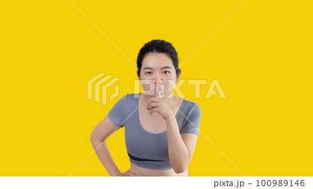 Asian woman doing silent gesture with finger, Noiseless symbol, Noisy mall, Hide a secret, Do not speak. shut your mouth, Noiseless signal transmission, Isolated on white background. 100989146