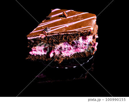 Chocolate cake with pink fruit cream on a black background. Chocolate cake with pink fruit cream on a black background. 100990155