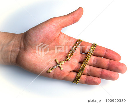 Christian cross with a gold chain on the palm of a man. 100990380