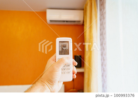 hand with the remote control of the air conditioner. hand with the remote control of the air conditioner. 100993376