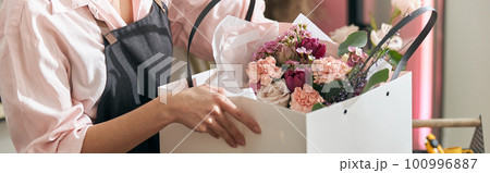 Professional florist young woman is doing bouquets at flower shop 100996887