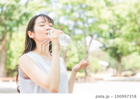 新緑の公園で散歩中に水分補給をする女性 新緑の公園で散歩中に水分補給をする女性 100997358