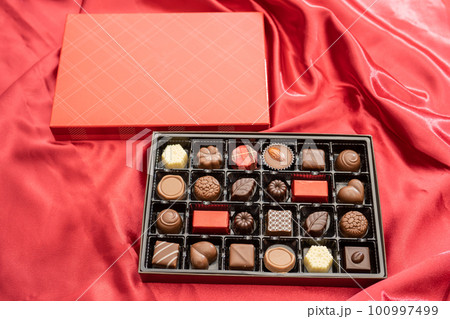 赤い布の上にある甘くて美味しい箱入りのお菓子のチョコレート 赤い布の上にある甘くて美味しい箱入りのお菓子のチョコレート 100997499