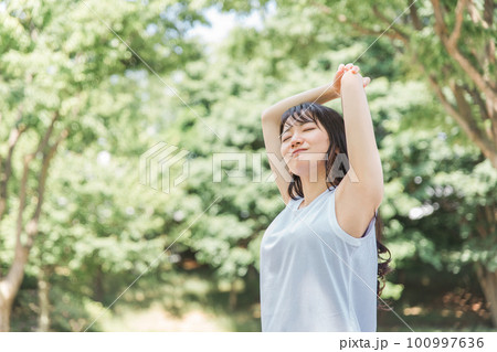 新緑の中でストレッチする女性 100997636