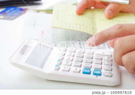 電卓でお金の計算をする男性の手元 100997819