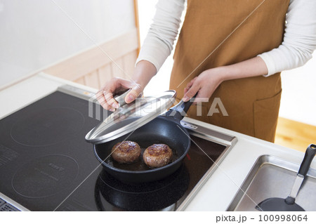 ハンバーグを焼く女性 100998064