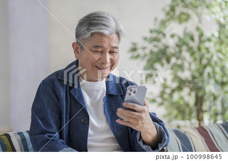 スマートフォンを持ったシニア男性 100998645