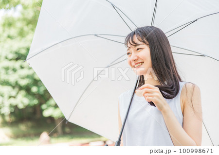 傘を差しながら髪を持つアジア人女性（ヘアケア） 100998671
