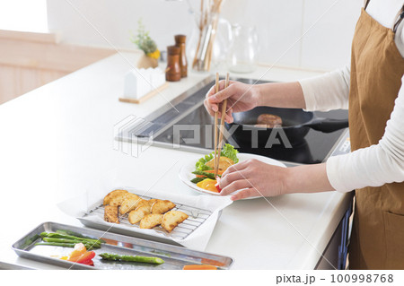 ハンバーグを盛り付ける女性 100998768