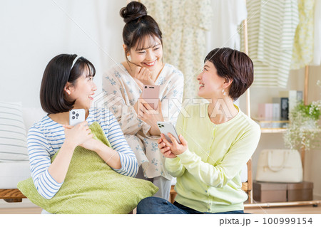 リビングでスマホを見る若い女性たち 100999154