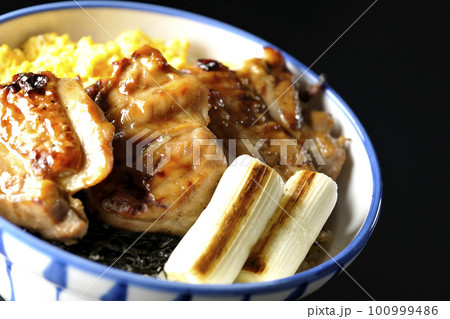 そぼろ玉子と焼き葱と刻み海苔も一緒に乗ってる照り焼きチキン丼を黒背景で撮影 100999486