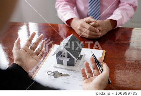 hand. The real estate agent explains the business contract 100999785