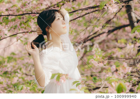 桜の木の下で佇む女性 100999940