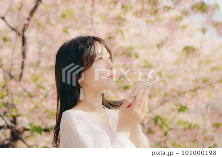 桜の木の下で化粧ボトルを持っている女性 桜の木の下で化粧ボトルを持っている女性 101000198