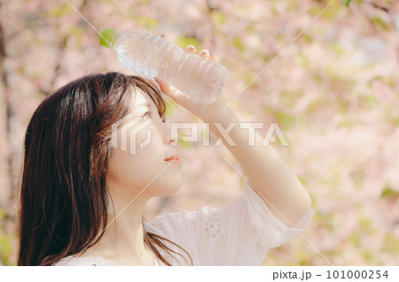 桜の木の下でペットボトルを持っている女性 101000254