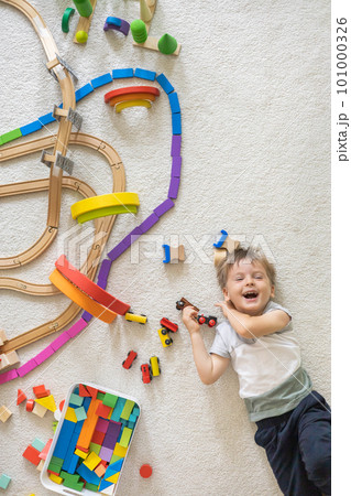 Preschool baby boy playing wooden Montessori materials rainbow arch railways at childish room. Top view. 101000326