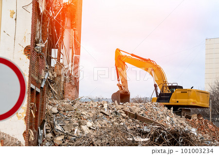 dismantling of the building, an excavator destroys an old building dismantling of the building, an excavator destroys an old building 101003234
