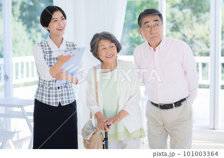 シニア夫婦に説明をする女性 101003364