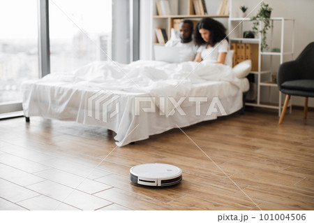 Robot vacuum cleaning floor in bedroom during daytime 101004506